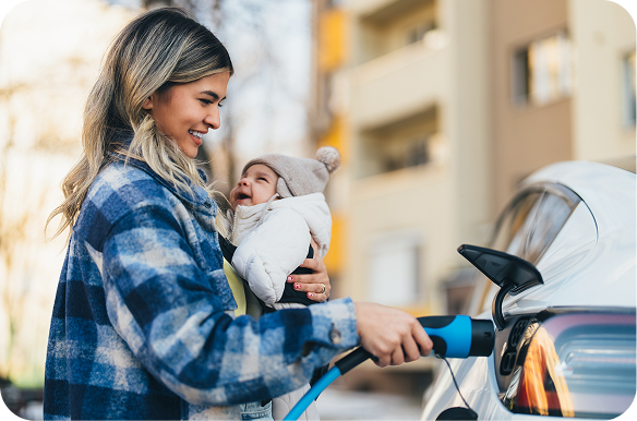 woman holding a baby while charging electric vehicles